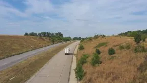 A commercial delivery truck transporting goods along a regional highway, representing agribusiness supply chain logistics and cold chain distribution.
